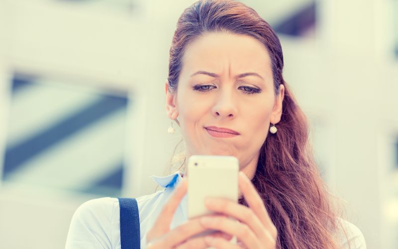 translation company-upset-sad-skeptical-unhappy-serious-woman-talking-texting-on-mobile-phone-min